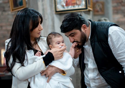A family with a baby enjoying a heartfelt moment during a religious ceremony indoors.